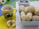 Des petits pains brésiliens au fromage déjà cuits accompagnés d'une tasse de café.