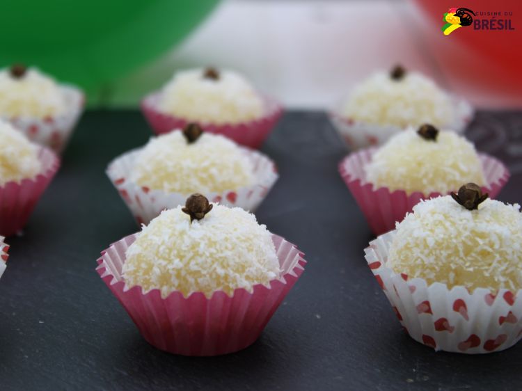 Les truffes brésiliennes (beijinhos) présentées sur une ardoise et avec deux ballons (un vert et un rouge) au fond.