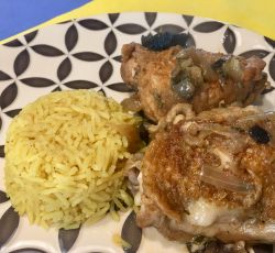 Une assiette avec du poulet à la bière et aux champignons et du riz au curry.